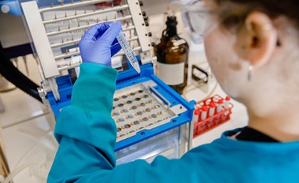 PhD student Katja Shimko in the laboratory Back of researcher in lab holding up test tube of liquid